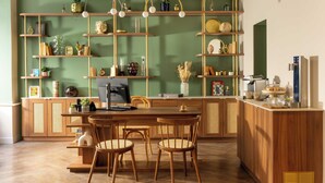 Una cocina con muebles de madera, estantes con adornos y una zona de comedor con sillas.