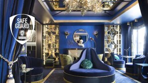 A luxurious room with a blue and gold color scheme, featuring a round seating area, a chandelier, and a mirror on the wall. - Maison Nabis by Happyculture (Paris)