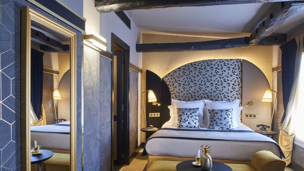 A hotel room with a large bed, two bedside tables, a small round table, and a mirror. - Maison Nabis by Happyculture (Paris)
