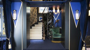 A staircase leading to a room with a green upholstered chair, a bird sculpture, and wall-mounted lamps. - Maison Nabis by Happyculture (Paris)