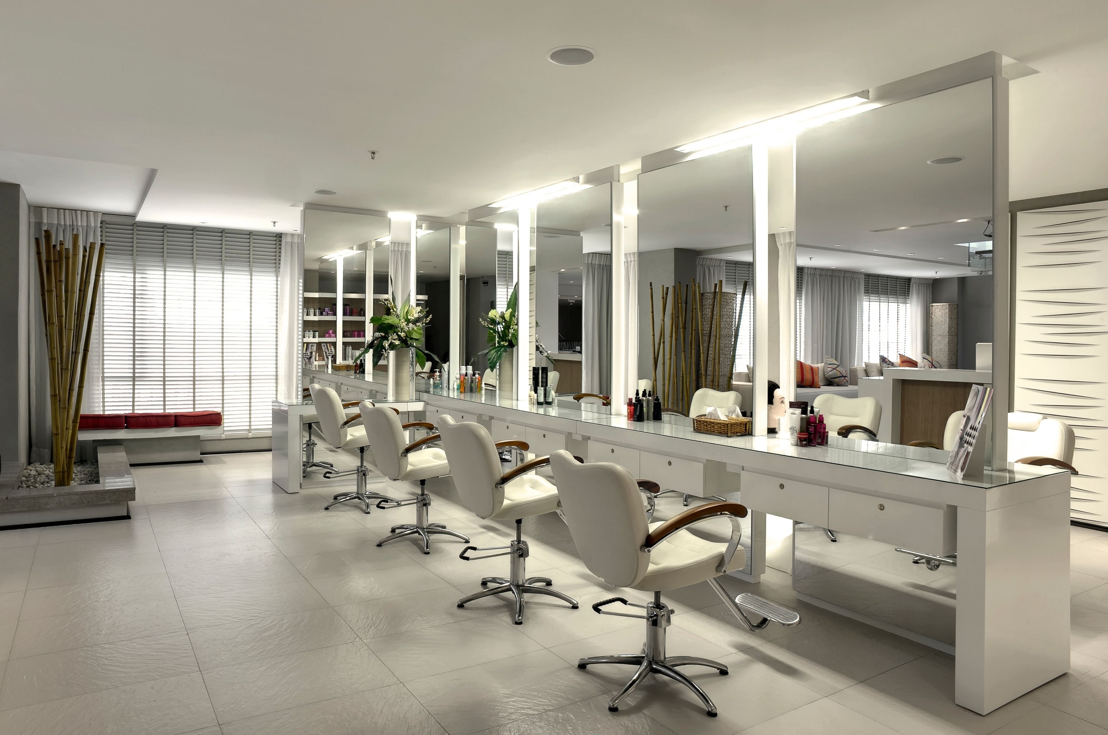 Ein moderner Friseursalon mit mehreren weißen Frisierstühlen, großen Spiegeln und einem klaren, minimalistischen Design.