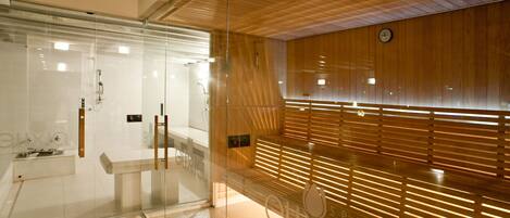 Un baño moderno con cabina de vidrio, pared de listones de madera y zona de lavamanos a la vista.
