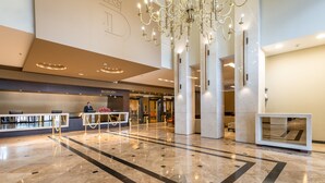 Un amplio vestíbulo con mostrador de recepción, un candelabro y un diseño moderno.