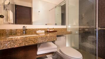 A modern bathroom with a granite countertop, a glass shower enclosure, and a white toilet.