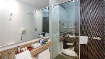 A modern bathroom with a glass-enclosed shower, a white toilet, a granite countertop, and a mirror.