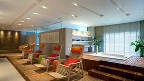 A modern spa area with wooden loungers, a hot tub, and a staircase leading to a balcony.