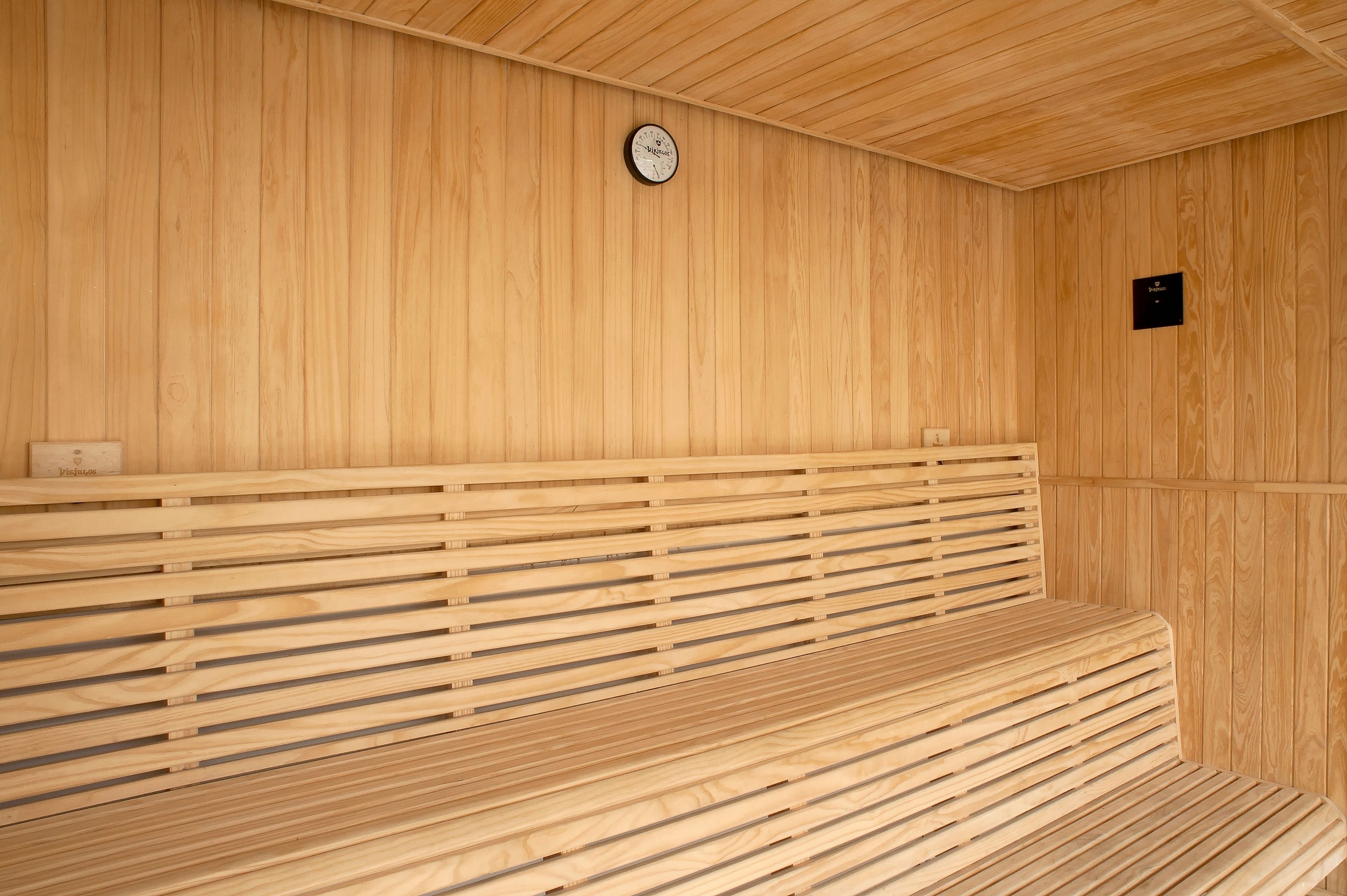 A wooden sauna with benches and a clock on the wall.