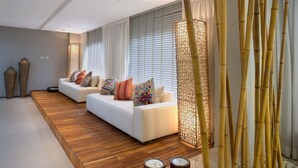 Una sala de estar moderna con un sofá blanco, piso de madera y almohadones decorativos.