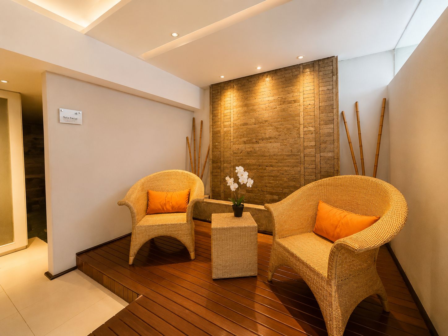 A modern room with two wicker chairs, a small table, and a potted orchid.