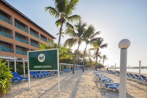 A beachside hotel with a sign reading 'whala!bocachica', blue lounge chairs, palm trees, and a clear sky. - Whala!boca Chica (Boca Chica)