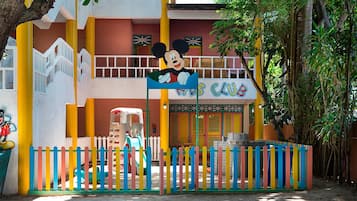 Un club pour enfants avec une clôture colorée, un toboggan et un panneau à l’effigie de Mickey Mouse.