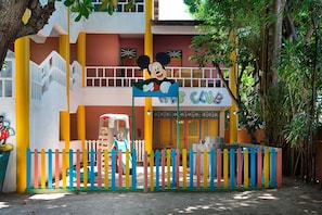 A children's club with a colorful fence, a slide, and a Mickey Mouse sign.