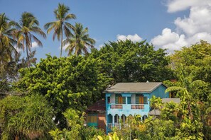 A two-story building with a blue facade, surrounded by lush greenery and palm trees. - Whala!boca Chica (Boca Chica)
