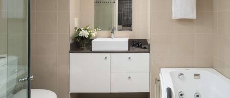 A modern bathroom with a glass shower enclosure, a white toilet, a vanity with a mirror, and a bathtub.