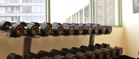 A rack of black dumbbells with red accents in a gym setting.