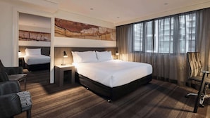 Een hotelkamer met een groot bed, een bureau, een stoel en uitzicht op de stad.