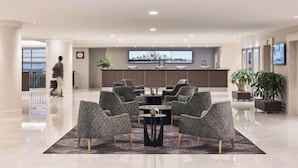 Een moderne lobby met een receptiebalie, een zithoek en grote ramen.