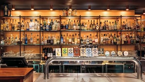 Een bar met meerdere flessen drank op planken en een tappunt.