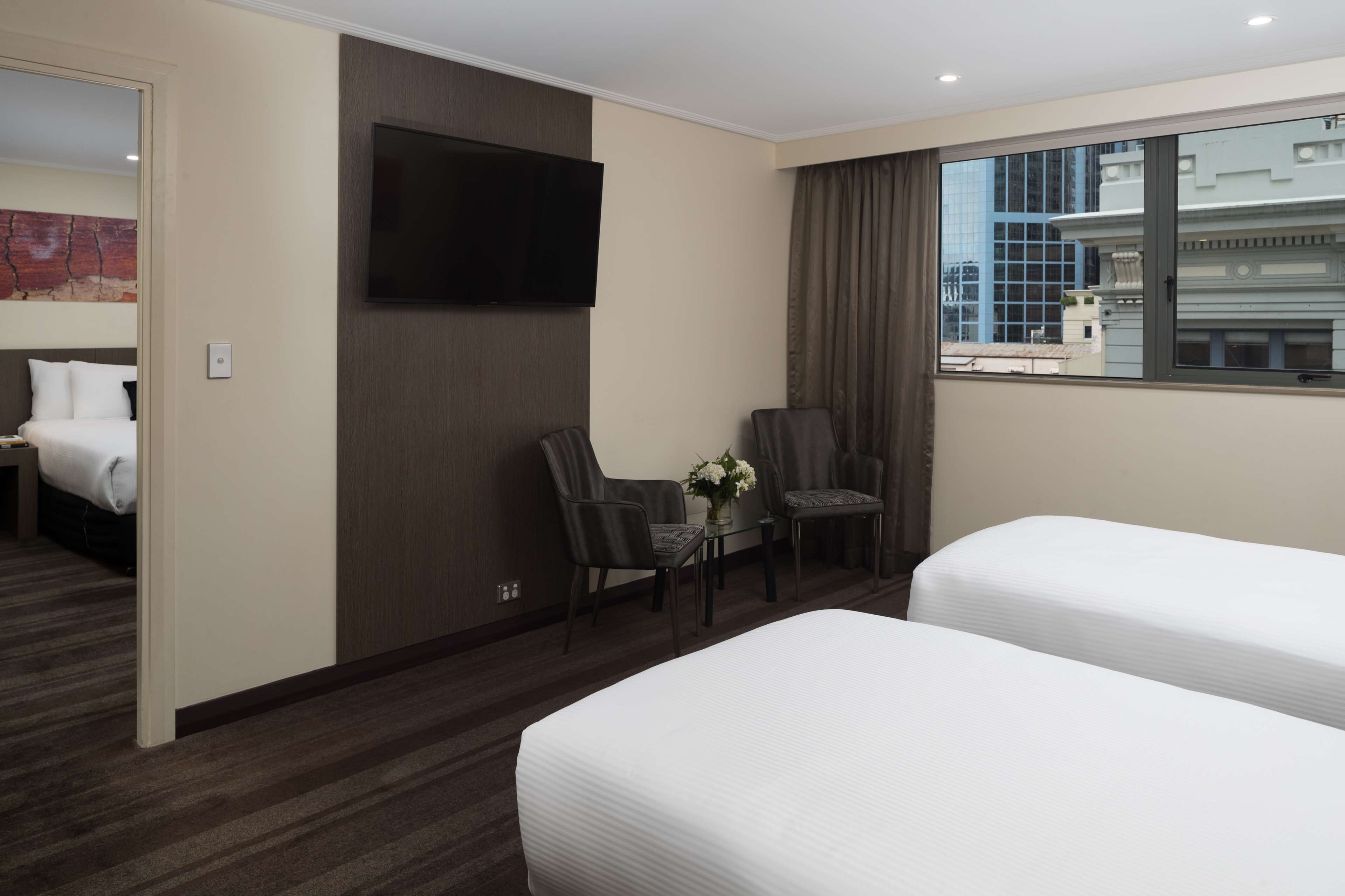 Une chambre d’hôtel avec deux lits, une télévision et une vue sur la ville.