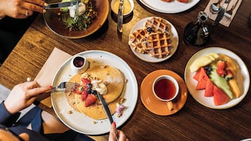 A dining table with various breakfast items including pancakes, waffles, and fruit.