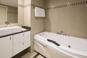 A modern bathroom with a white sink, mirror, and bathtub.