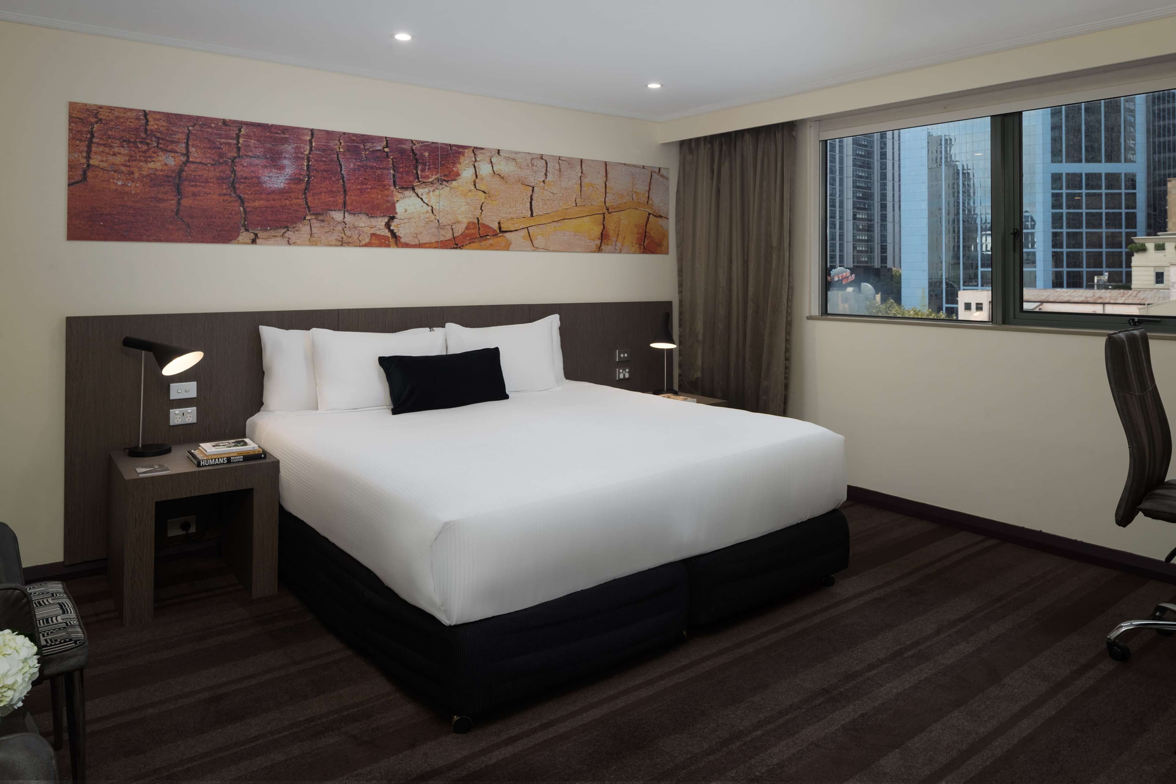 Une chambre d’hôtel avec un grand lit, une table de chevet, un bureau et une chaise.