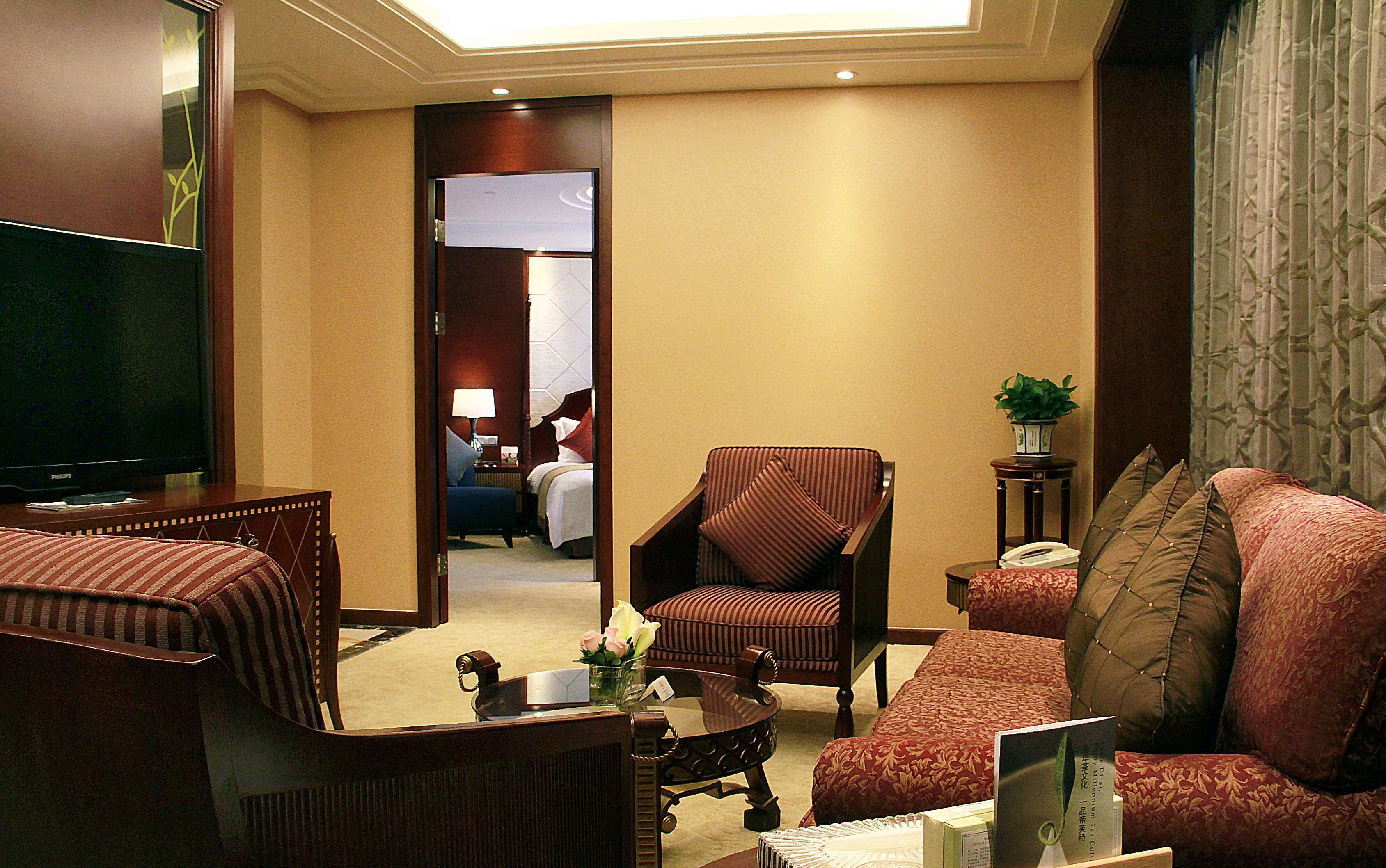 Une chambre d’hôtel équipée d’une télévision, d’un canapé, d’un fauteuil et d’un lit.