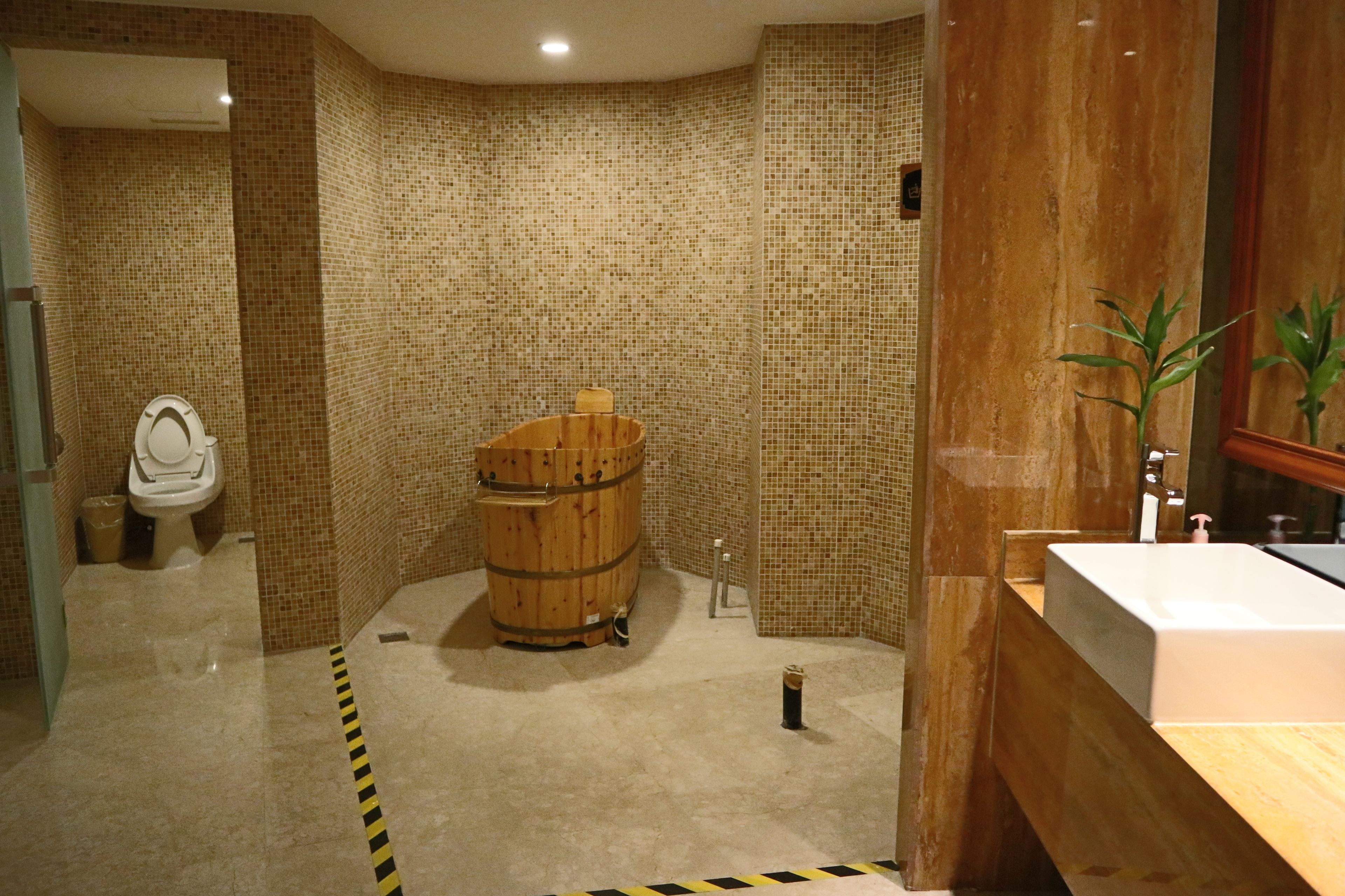 Une salle de bain équipée d’un tonneau en bois, de toilettes et d’un lavabo.