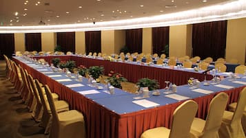 A conference room with a long table, chairs, and various items like water bottles and papers.