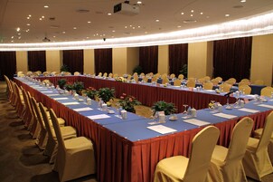 A conference room with a long table, chairs, and various items like water bottles and papers.
