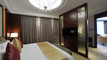 A hotel room with a large bed, a TV, a mirror, and a view of the outside.