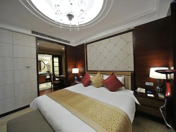 A hotel room with a large bed, a chandelier, a mirror, and a bedside table with a lamp. - Central Hotel Shanghai (Shanghai)
