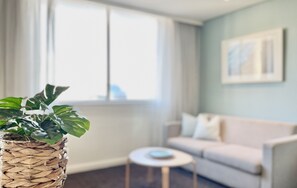 A living room with a sofa, a small round table, and a potted plant. - Coogee Sands Hotel & Apartments (Sydney)