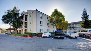 A parking lot with several cars and a multi-story building with balconies.