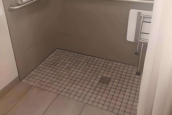 A small, tiled bathroom with a handrail and a towel rack.