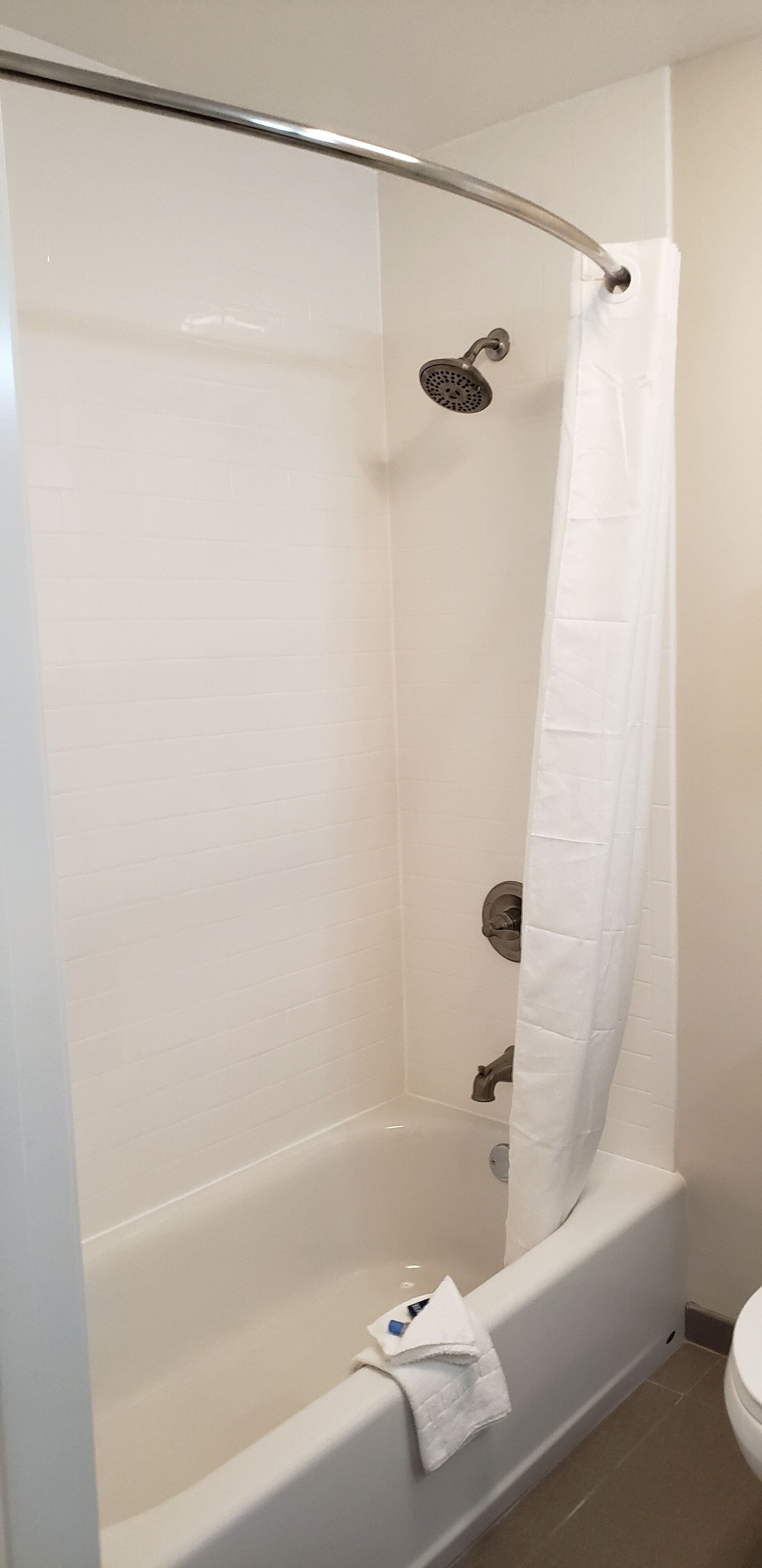 A bathroom with a bathtub, a showerhead, and a toilet.
