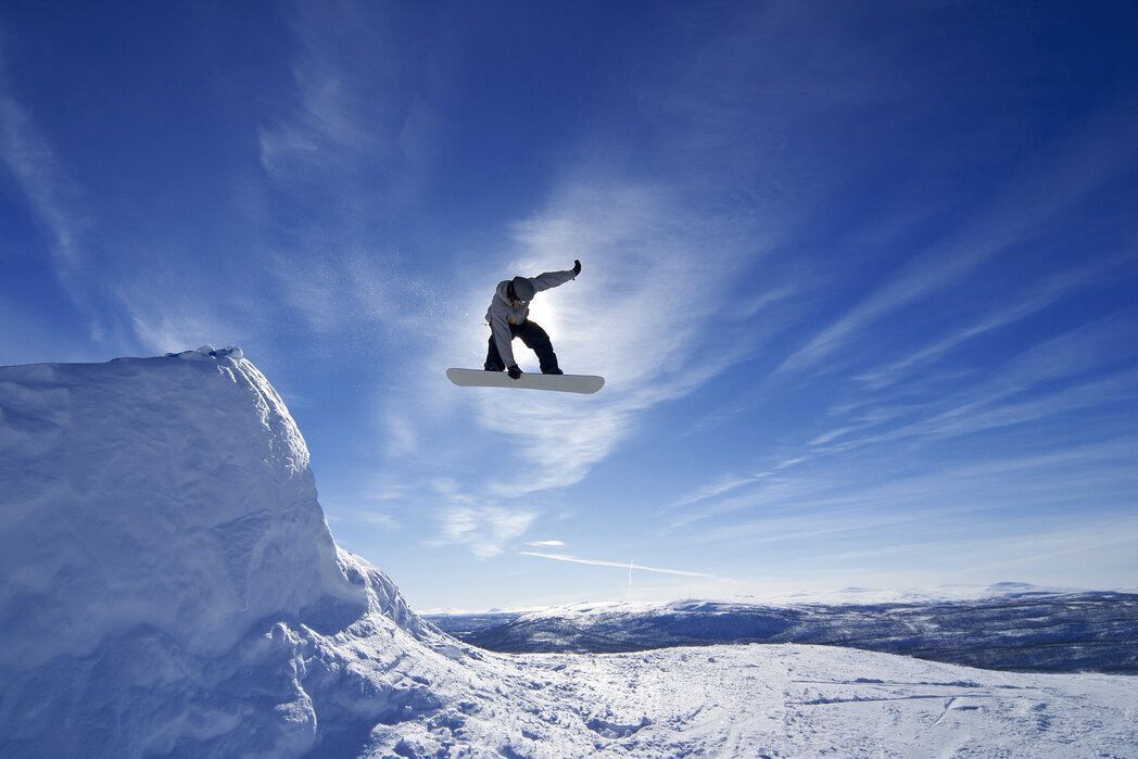 A snowboarder mid-air above a snowy mountain.