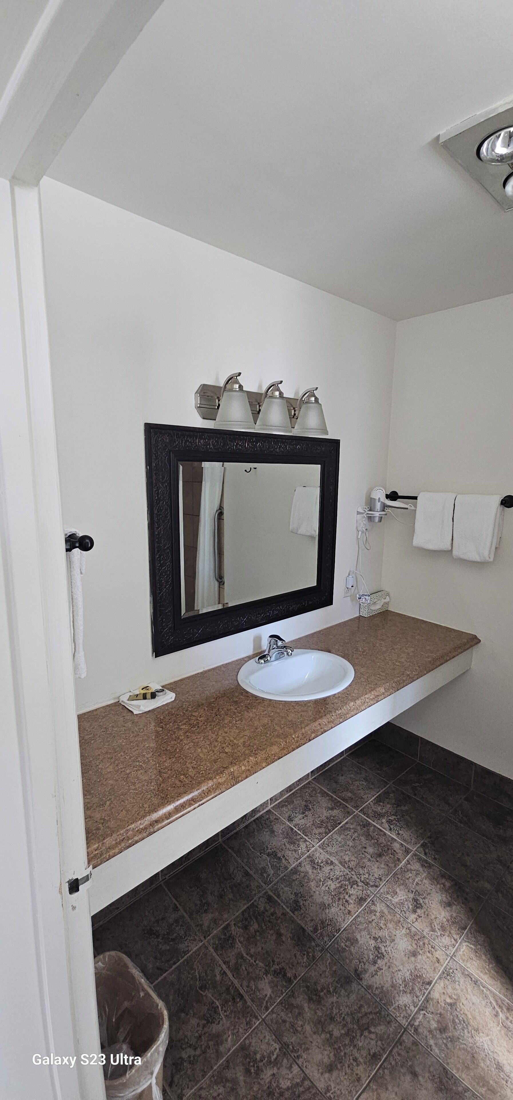 A bathroom with a white sink, a mirror with a black frame, and a towel rack.