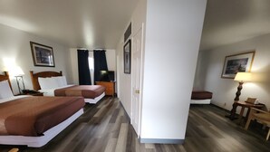 Quarto de hotel com duas camas, televisão, escrivaninha e uma cadeira.