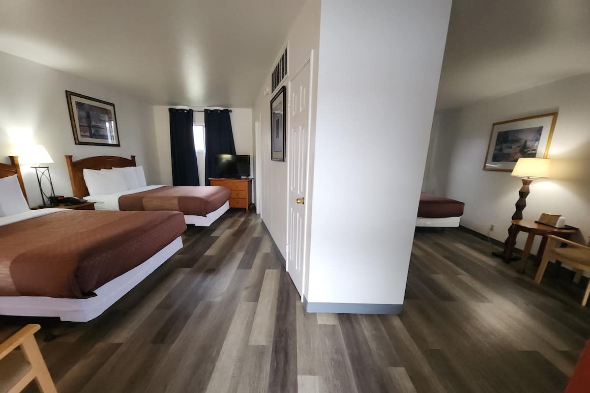 A hotel room with two beds, a TV, a desk, and a chair.