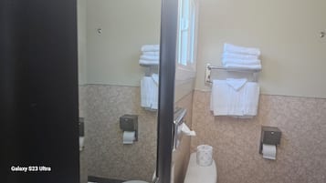 A bathroom with a toilet, two towel racks with folded towels, and two paper towel dispensers.