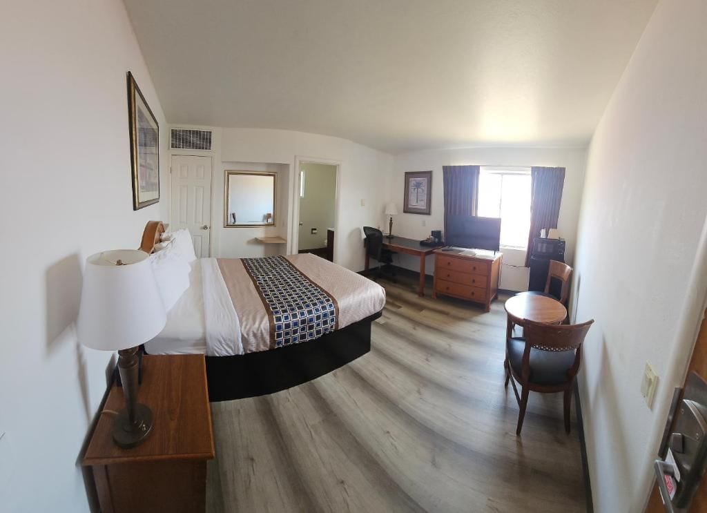 Een hotelkamer met een bed, bureau, stoel en een eettafeltje.