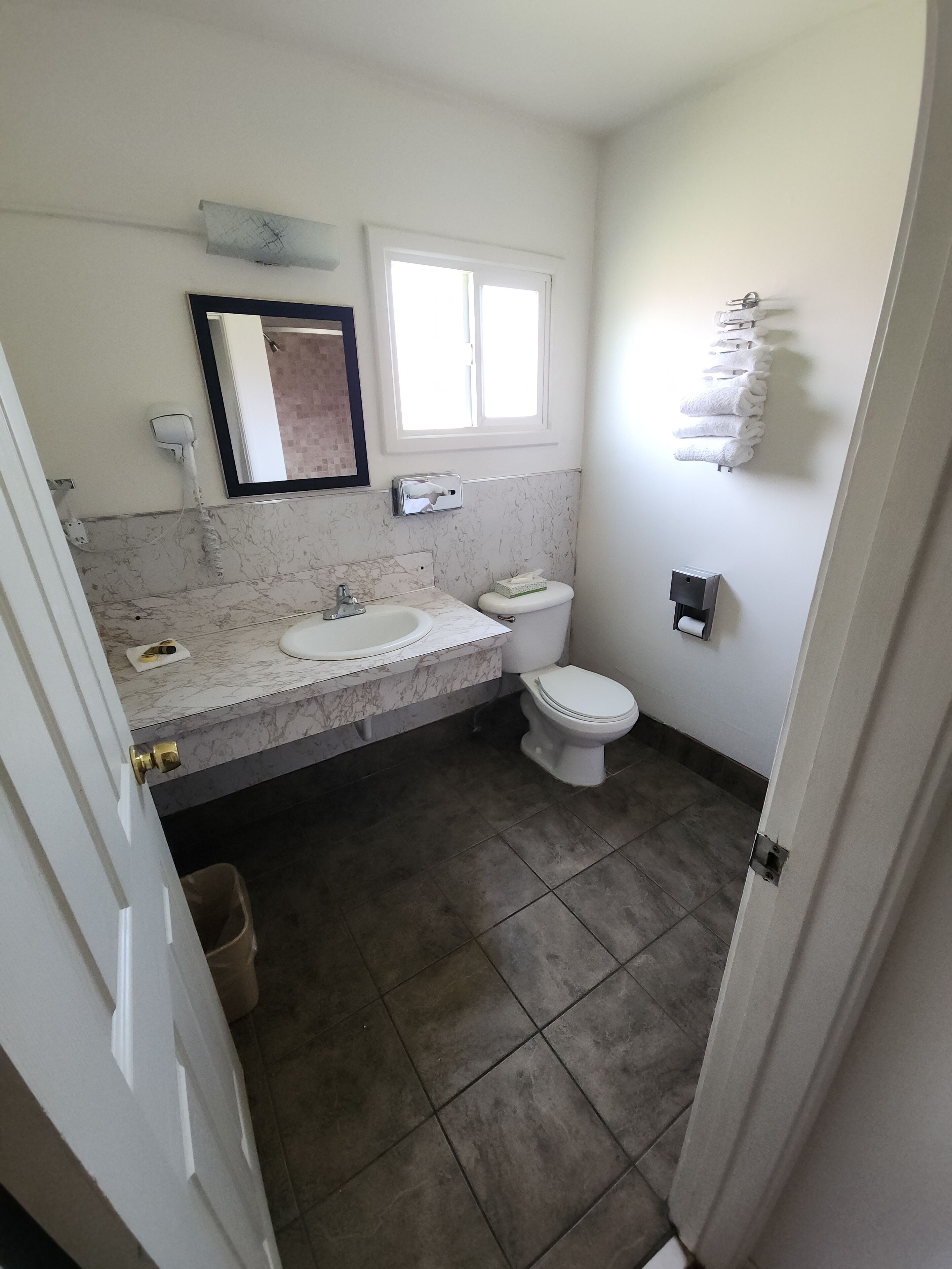 A bathroom with a marble sink, a toilet, and a window.