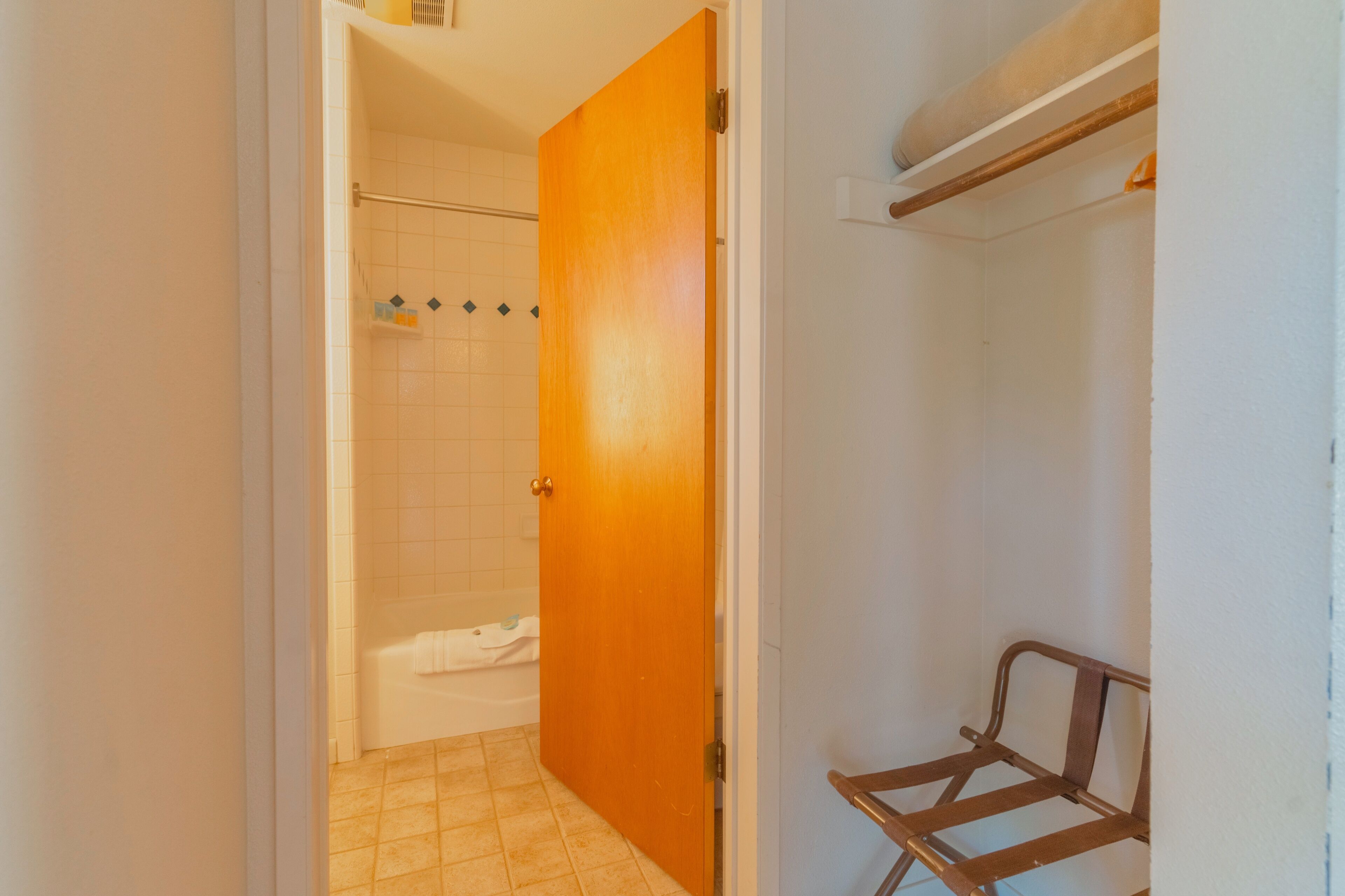 A bathroom with a shower, a wooden door, and a metal bench.
