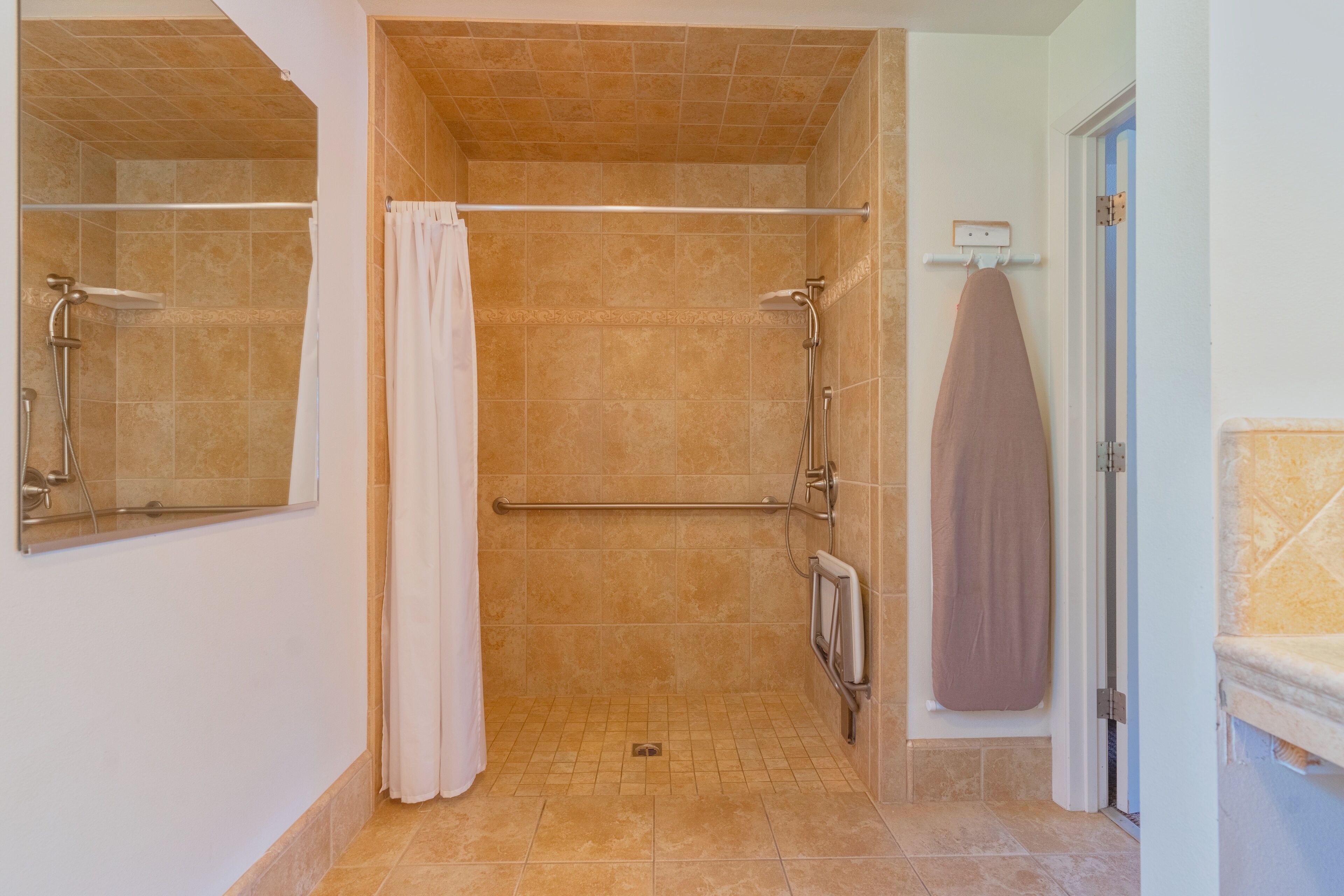 A bathroom with a shower, a towel rack, and a mirror.