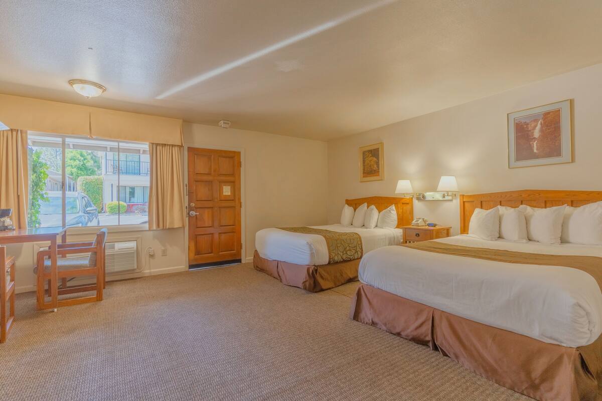 A hotel room with two beds, a desk, and a chair.