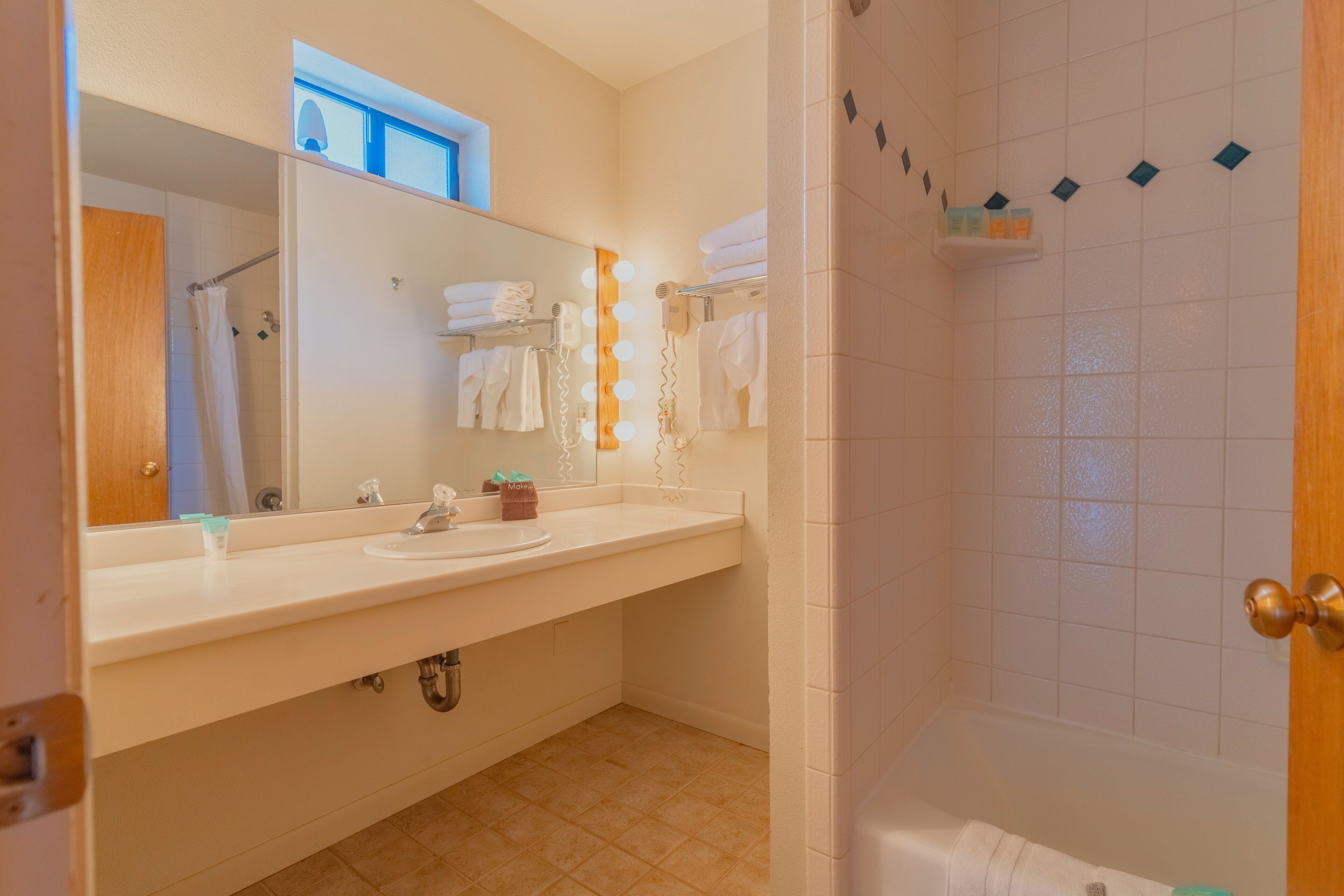 A bathroom with a sink, mirror, and shower.
