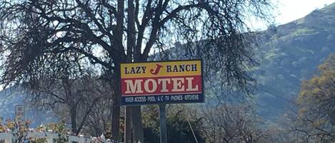 A sign for the Lazy J Ranch Motel with amenities including river access, pool, A/C, phones, and kitchens.