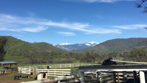 A fenced outdoor area with a shelter, a small building, and a view of snow-capped mountains in the background. - Lazy J Ranch Motel (Three Rivers)