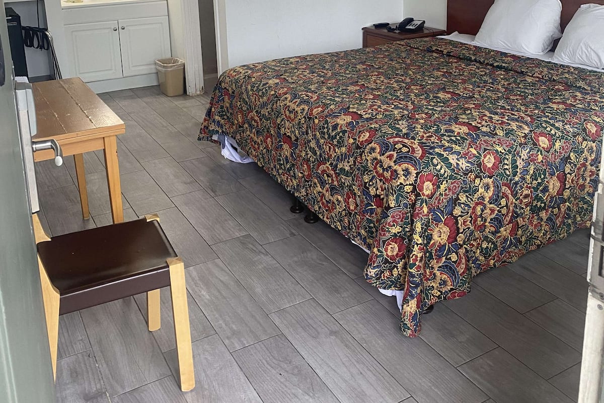 A hotel room with a bed, a desk, and a mirror.